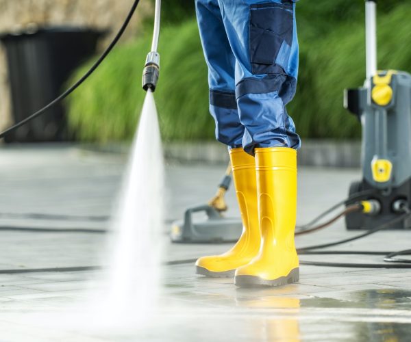 A Men Washing Residential Bricks Made Driveway and Paths Using Powerful Pressure Washer.