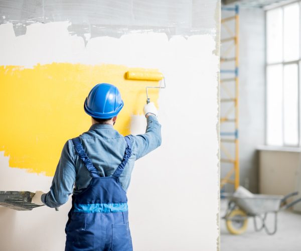 Workamn painting wall indoors